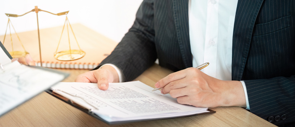 A lawyer completing legal paperwork with judicial scales in the background